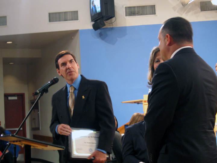 Dr. Keith Astuto addresses the Miami-Dade School Board, alongside board member Dr. Marta Pérez (partially obscured) and South Miami High principal Gilberto Bonce.